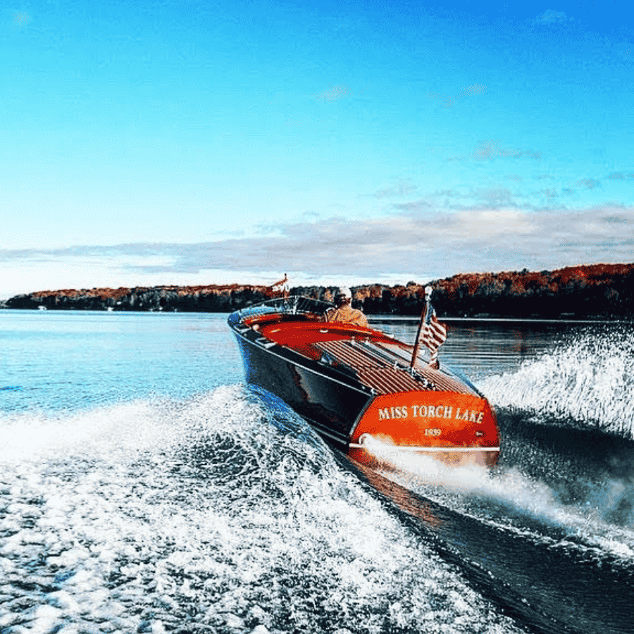 wooden boat with wake on lake blue sky